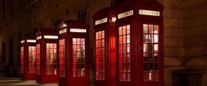 Five red telephone boxes lit up at night. Use one to book a massage in London with an Asian masseuse of your choice