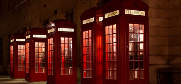 Five red telephone boxes lit up at night. Use one to book a massage in London with an Asian masseuse of your choice