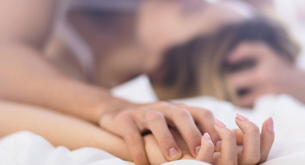 A couple lay on a bed kissing during a body to body massage