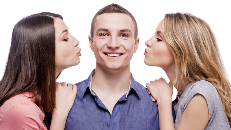 A man stood inbetween two women who are about to give him a 4 hands massage