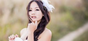 A sexy Chinese massage therapist with a white feather in her hair