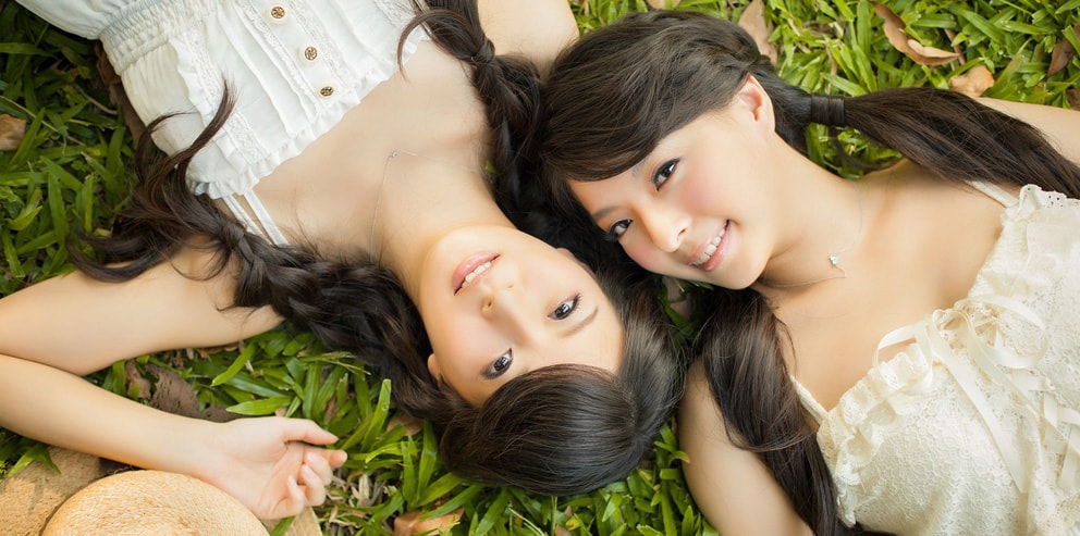 Two Asian massage therapists lay on the floor outside